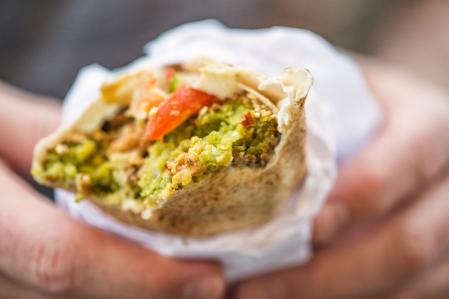 un uomo tiene in mano falafel mahshi in un involucro di khubz pita